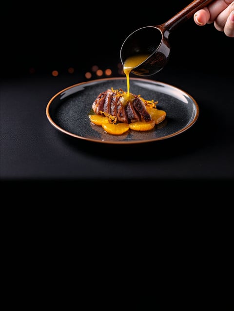 Cookbook dish styled and photographed with sauce being poured, showing professional food styling